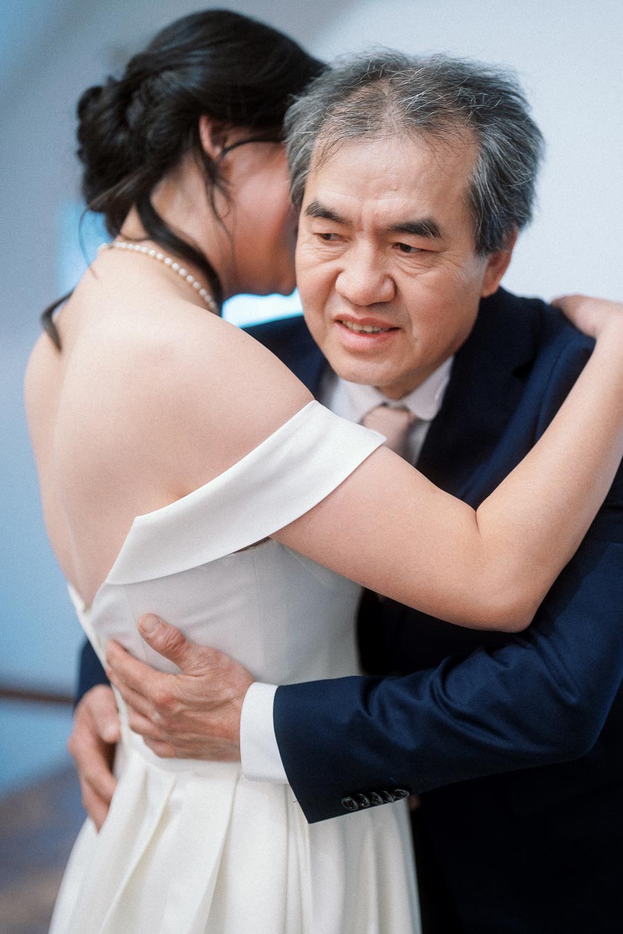 Bride in an off-shoulder dress embracing an older man in a suit