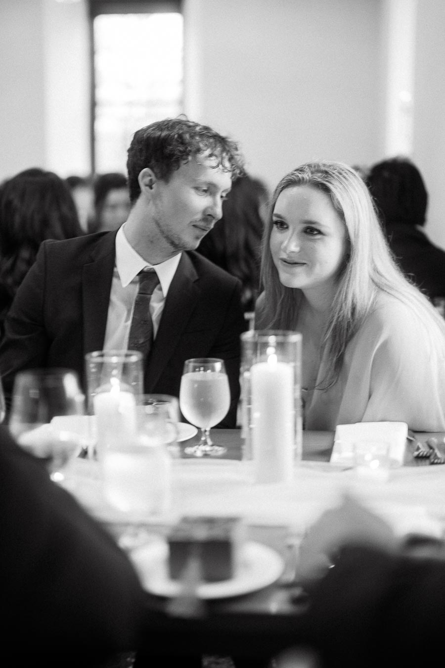 Couple seated close together at a candlelit table during an engagement photoshoot
