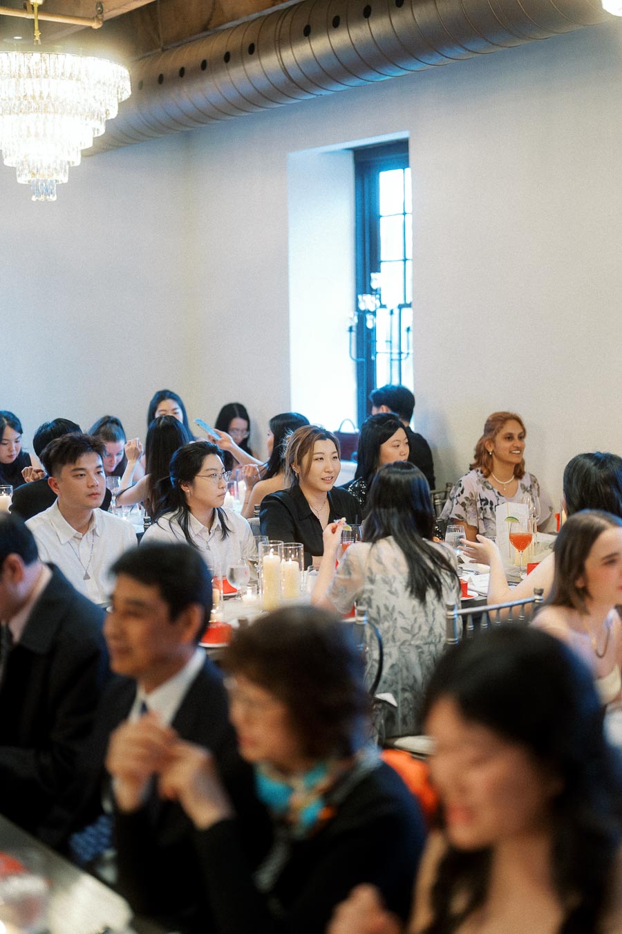 Guests seated at candlelit tables during an indoor engagement celebration