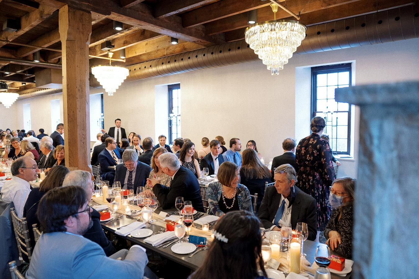 Guests seated at long reception tables in a warmly lit dining room