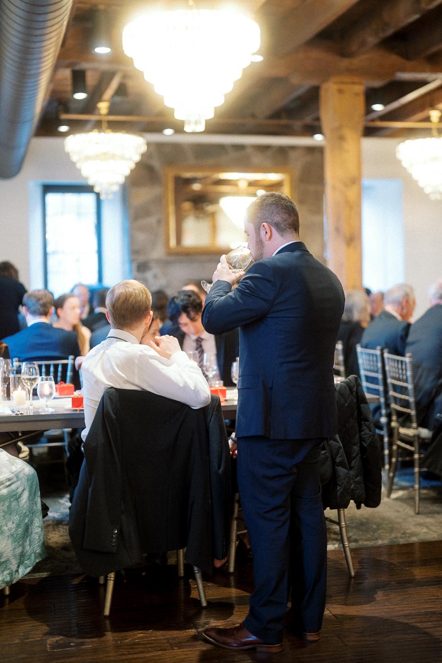 Man in a suit drinking at a formal indoor dinner reception