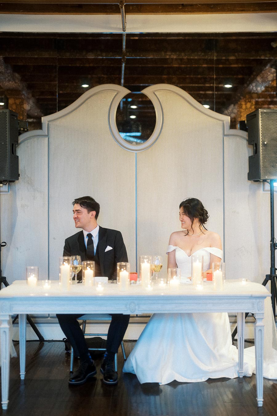 Couple seated at a candlelit reception table in formal wedding attire
