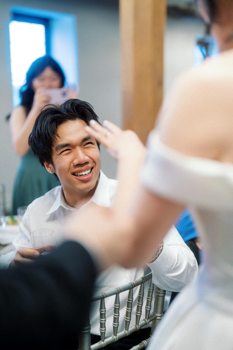 Man smiling at partner showing a ring during an indoor engagement gathering
