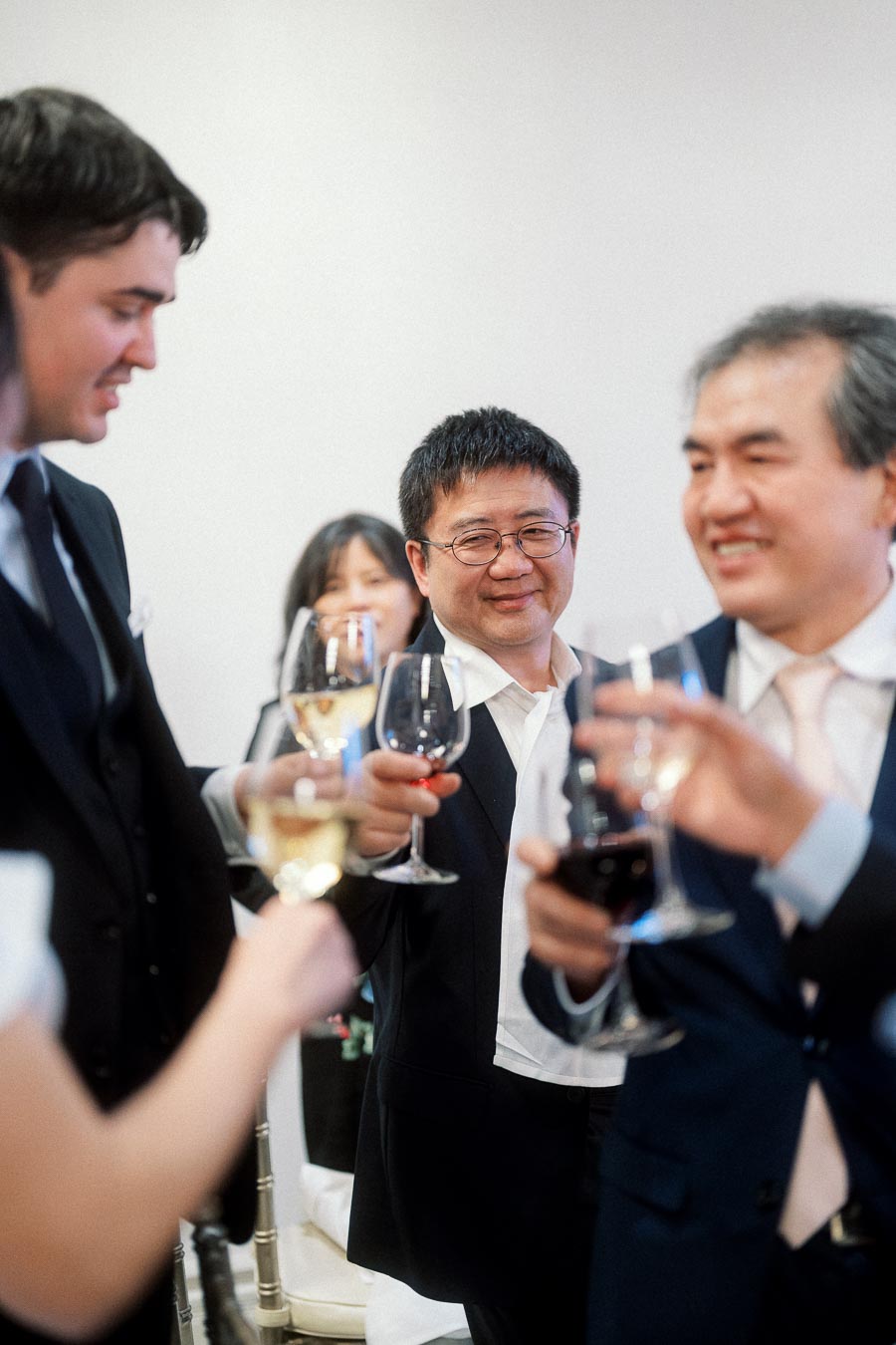 Guests in formal attire raise wine glasses for a celebratory toast.