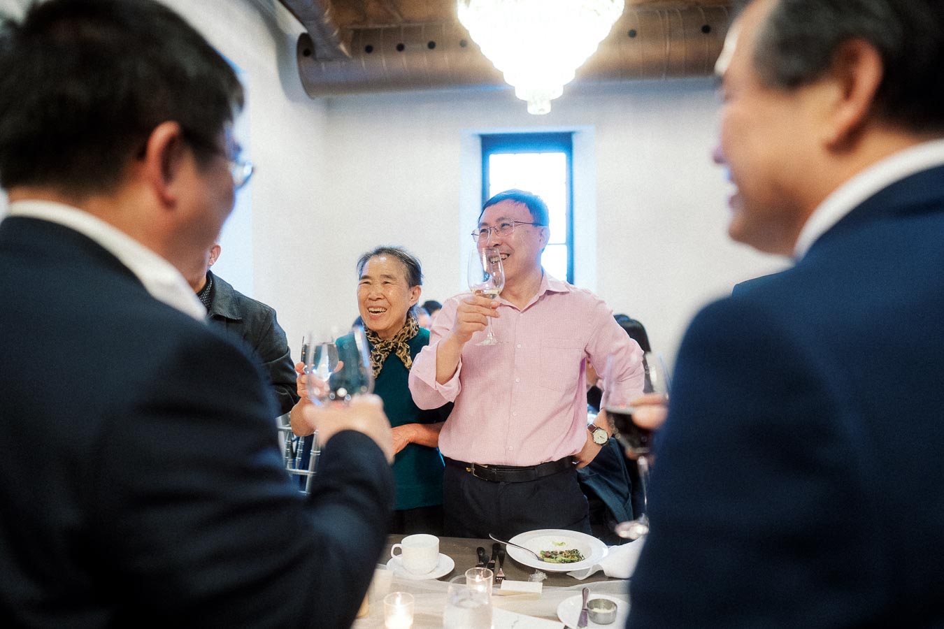 Guests laughing and raising glasses during an indoor celebration toast