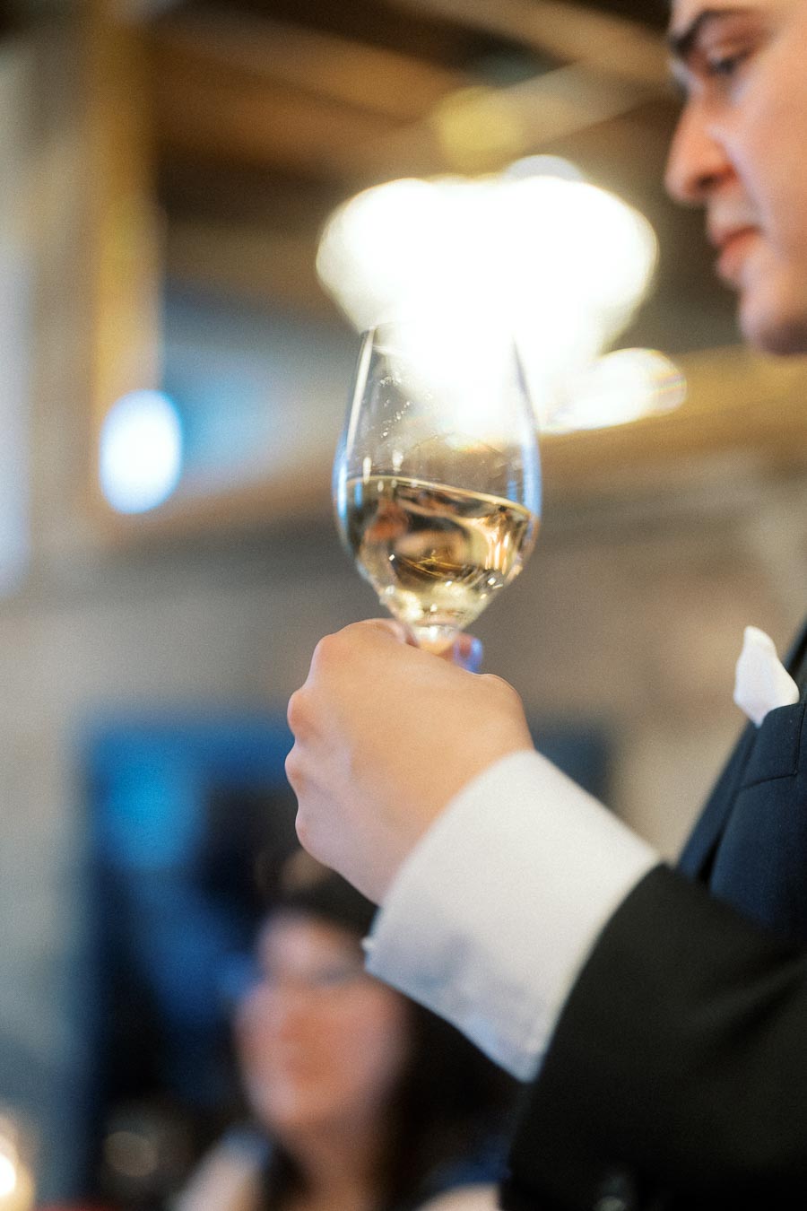 Man in a suit holding a wine glass during an indoor celebration