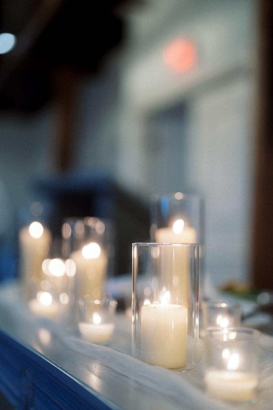 Lit white candles in glass holders arranged on a table