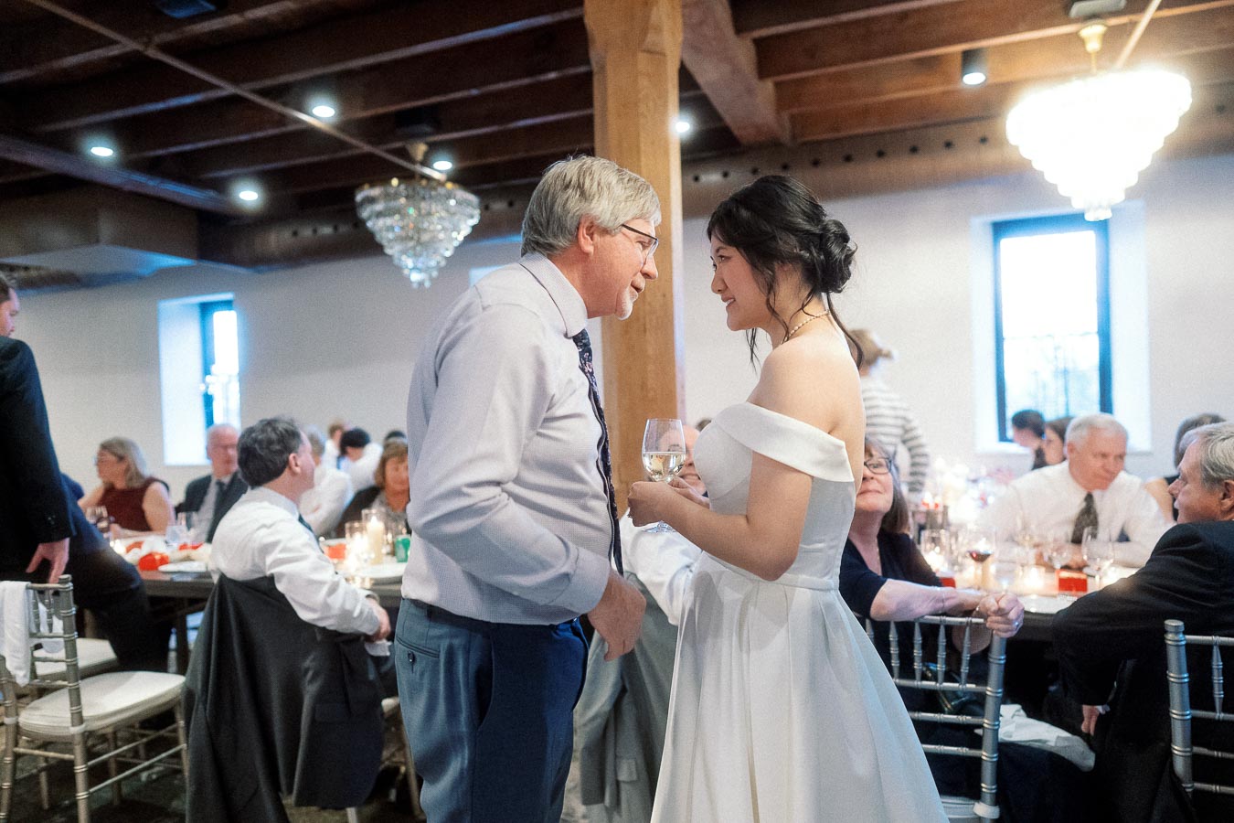 Bride smiling and talking with an older guest during a reception dinner