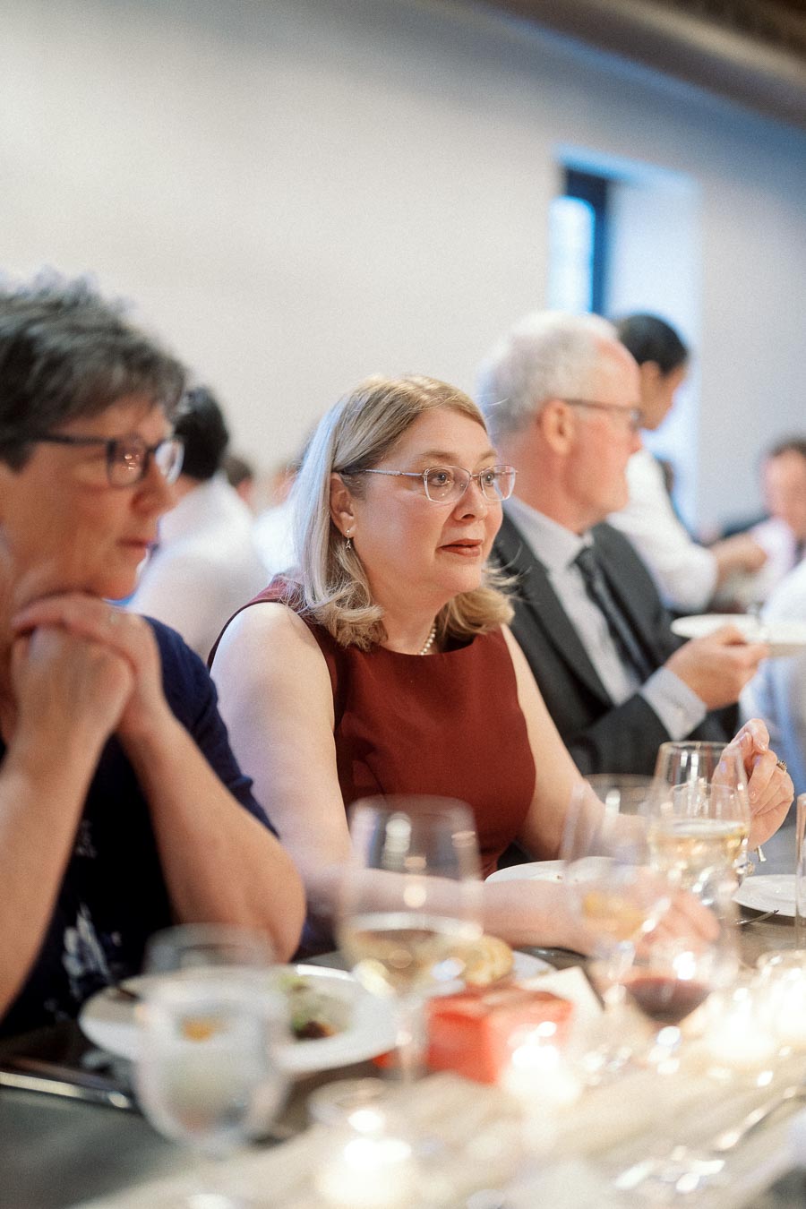 Guests seated at a dinner table during a formal indoor celebration.