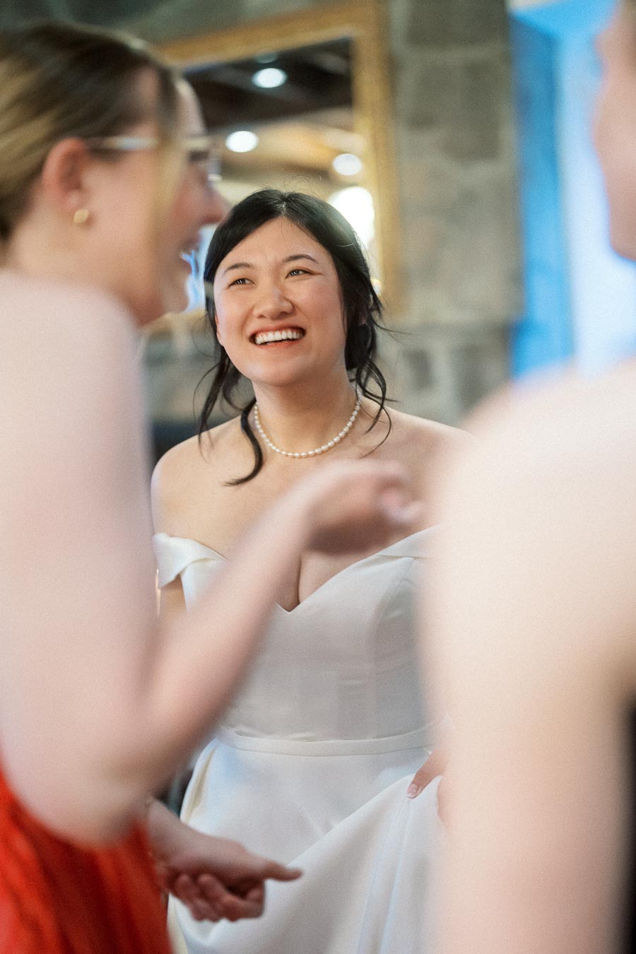 Smiling bride in a white dress chatting with two people indoors