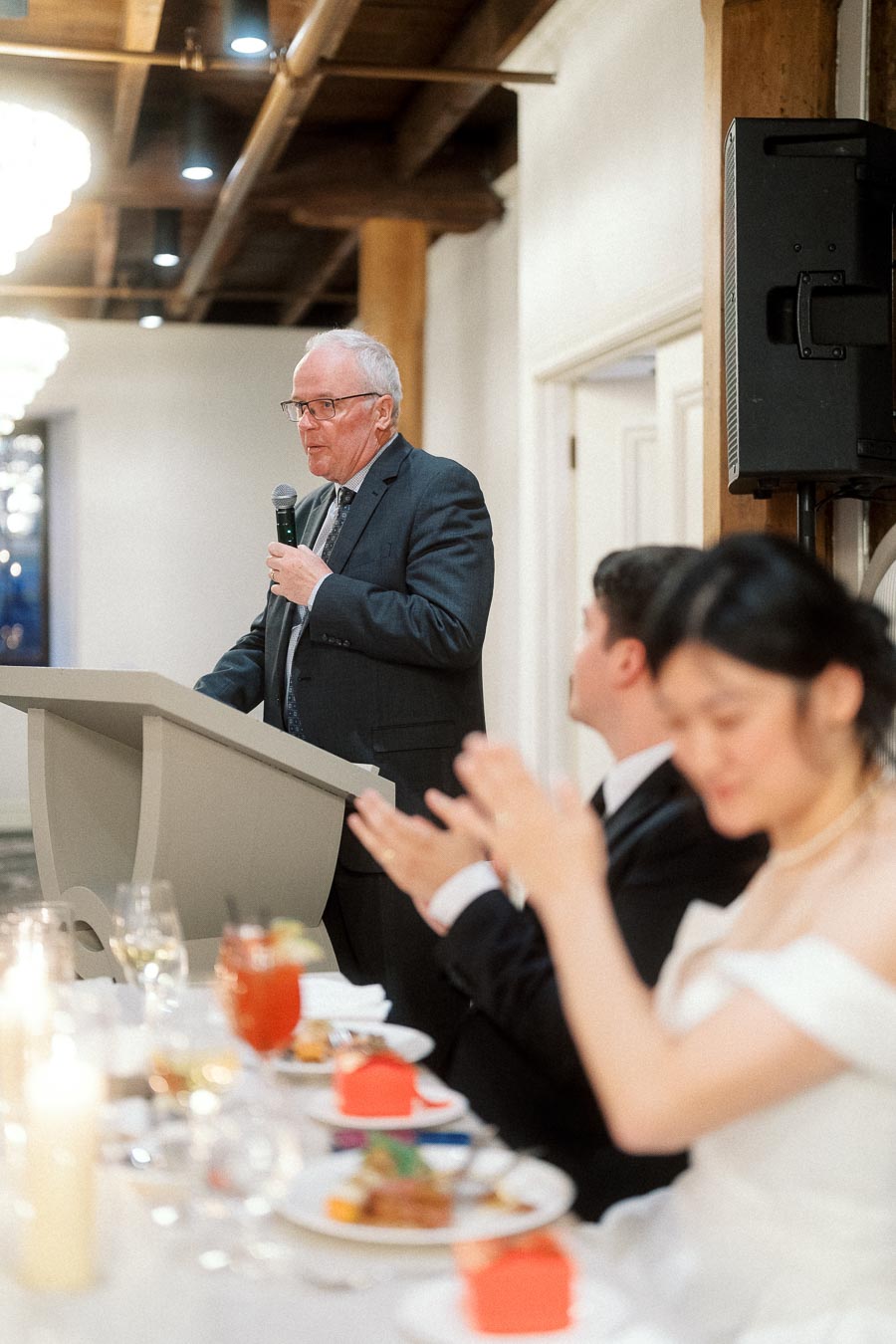 Man giving a speech at a reception while seated guests applaud