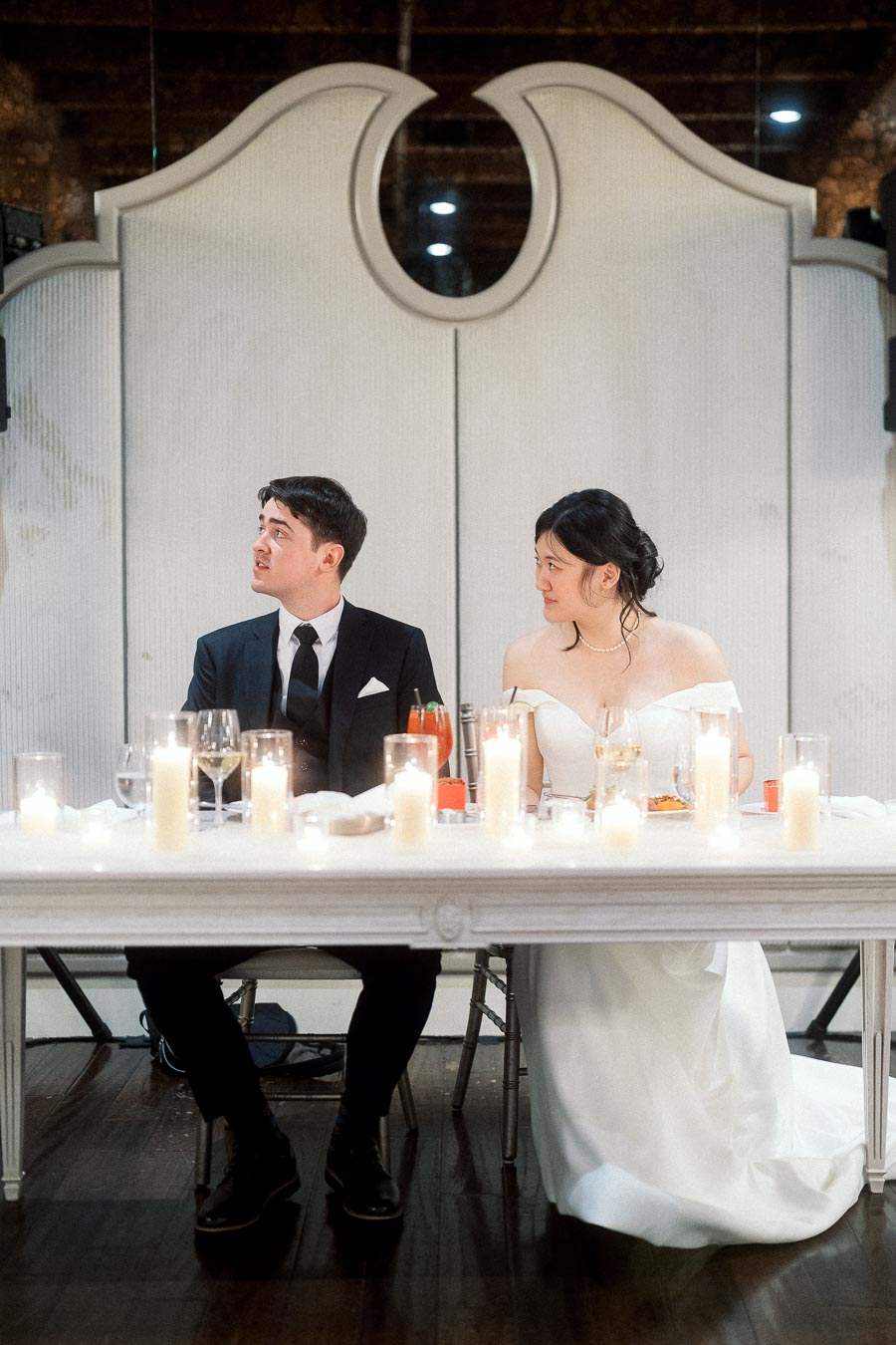 Couple in formal attire seated at a candlelit reception table