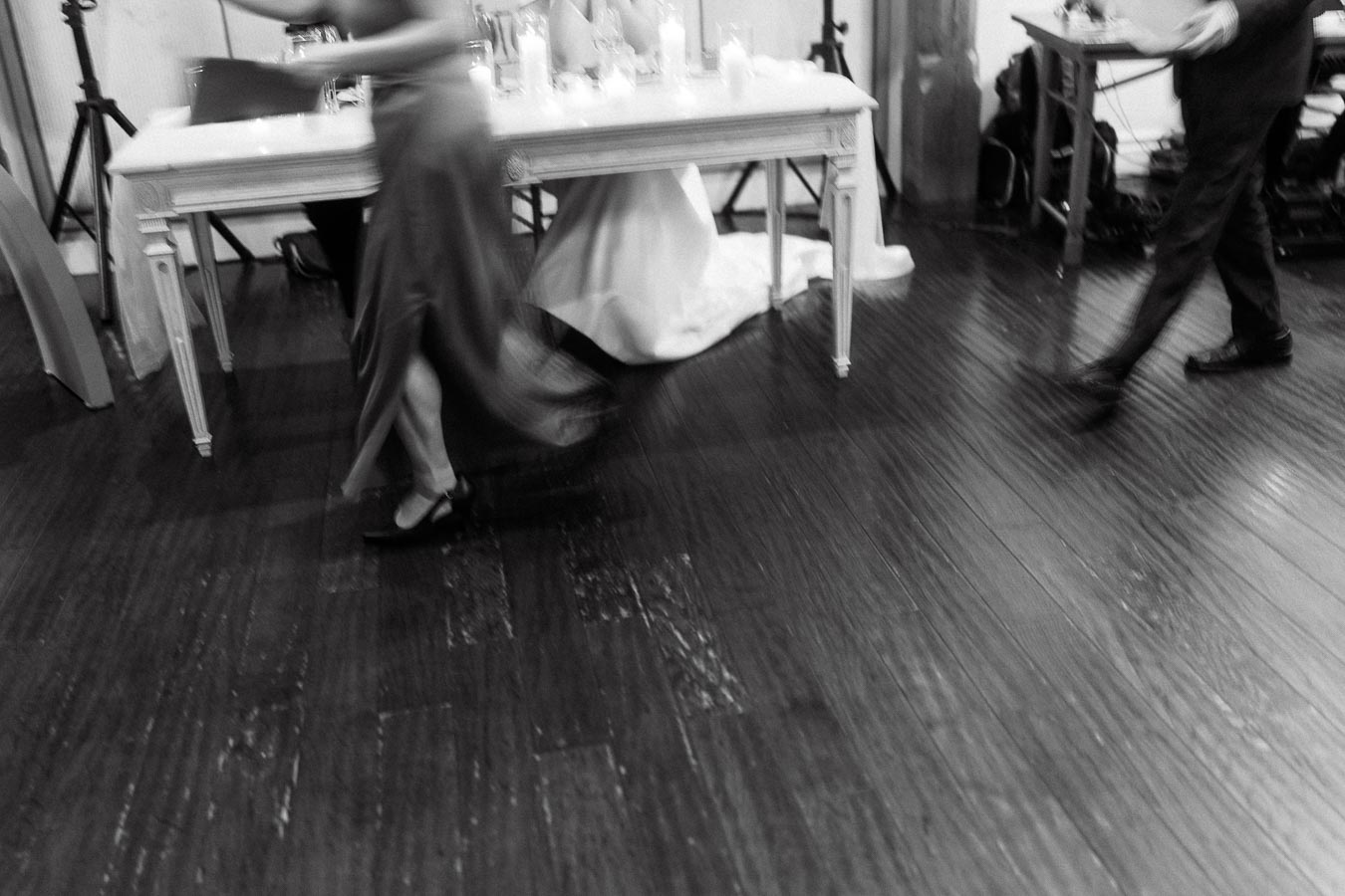 Blurred black-and-white scene of people walking past a decorated table indoors