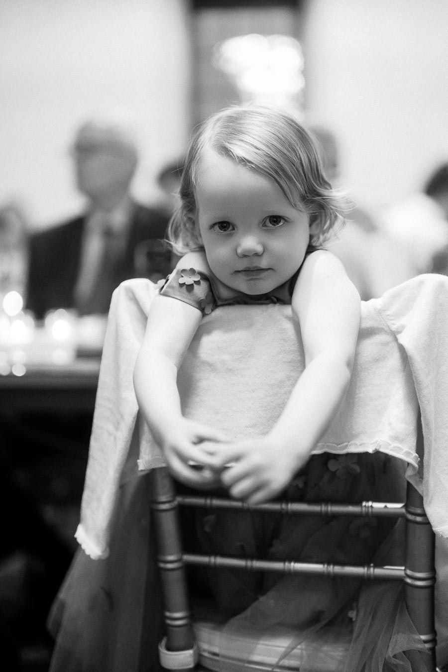Young child leaning over the back of a chair during an indoor event