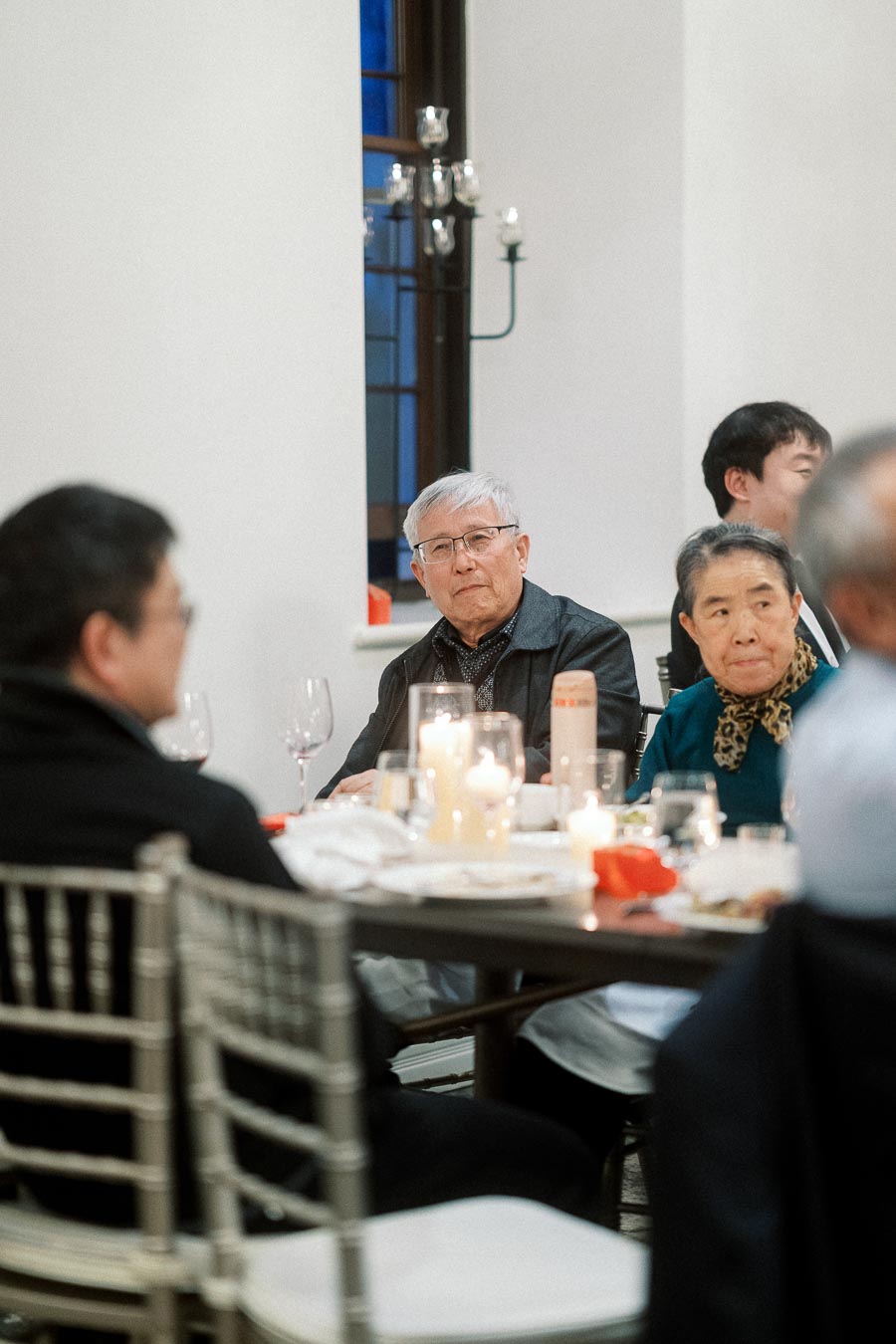 Guests seated around a candlelit dinner table during an indoor celebration