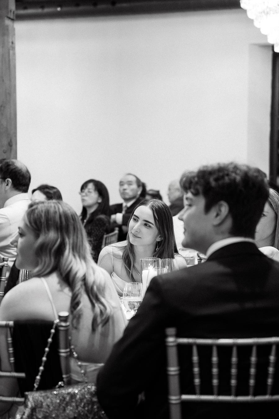 Guests seated at a formal indoor event in black and white