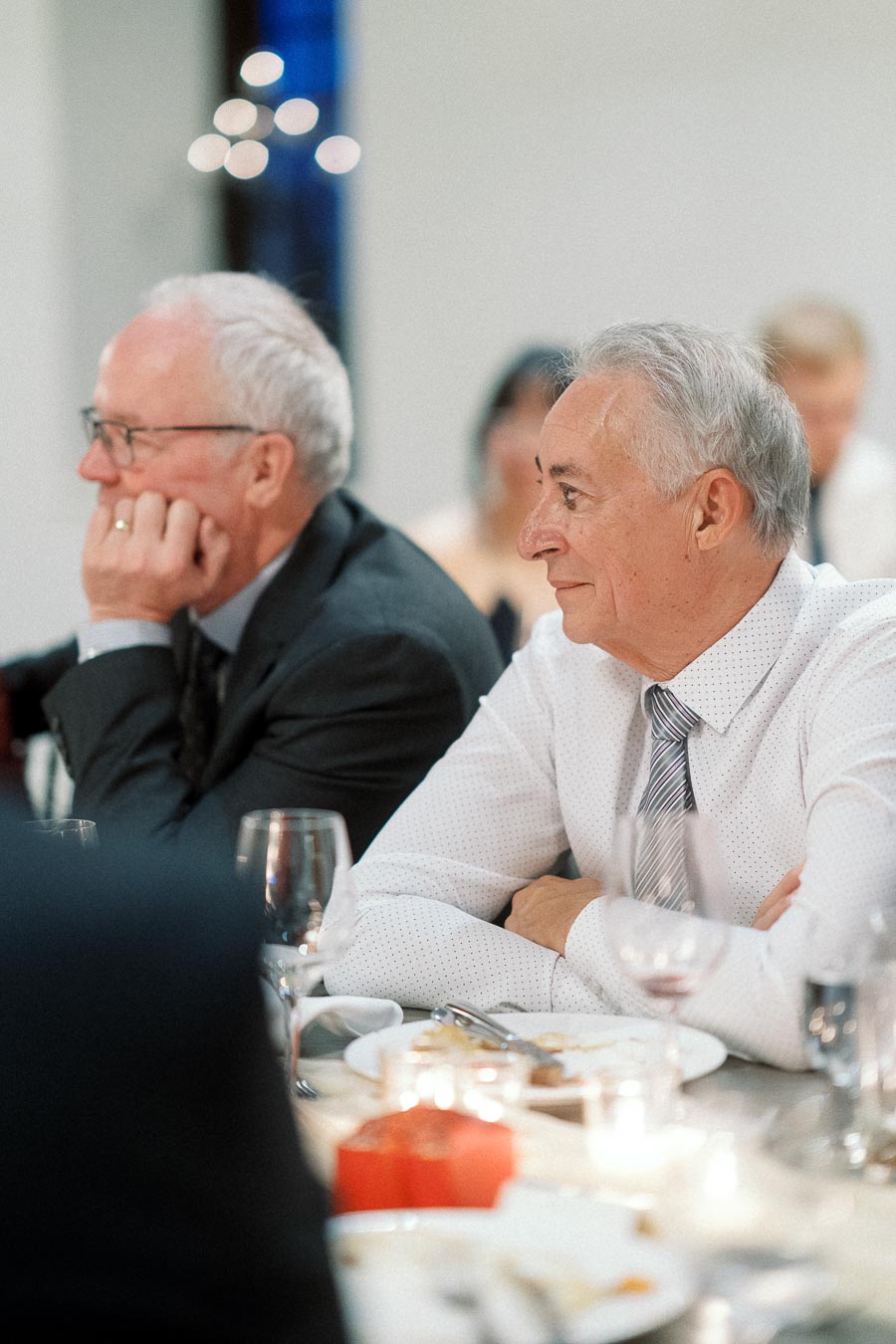 Two older men seated at a formal dinner table during an event.