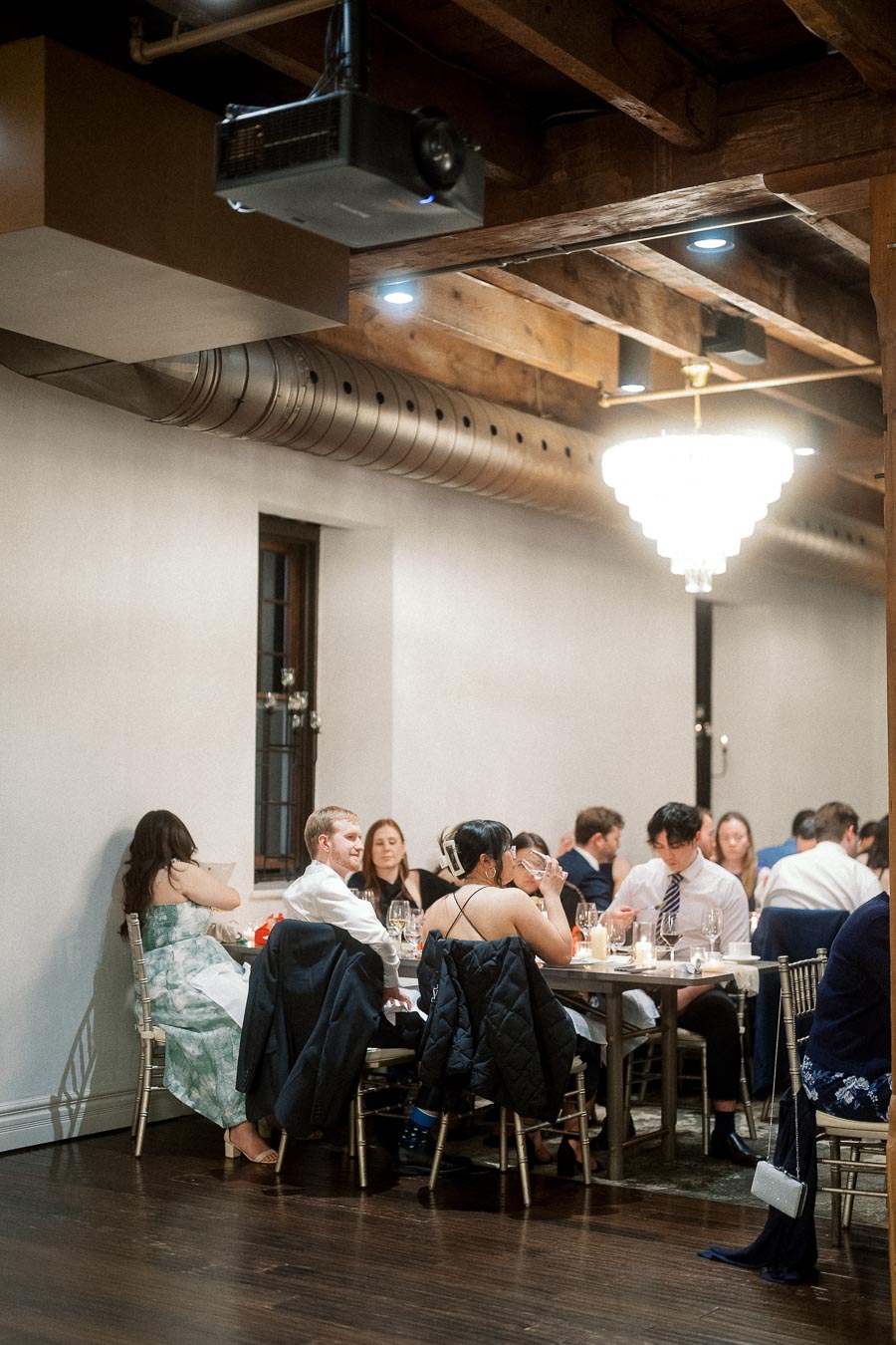Guests seated at round tables during an indoor engagement celebration dinner