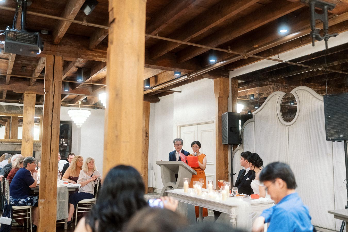 Two guests giving a speech at a podium during an indoor celebration