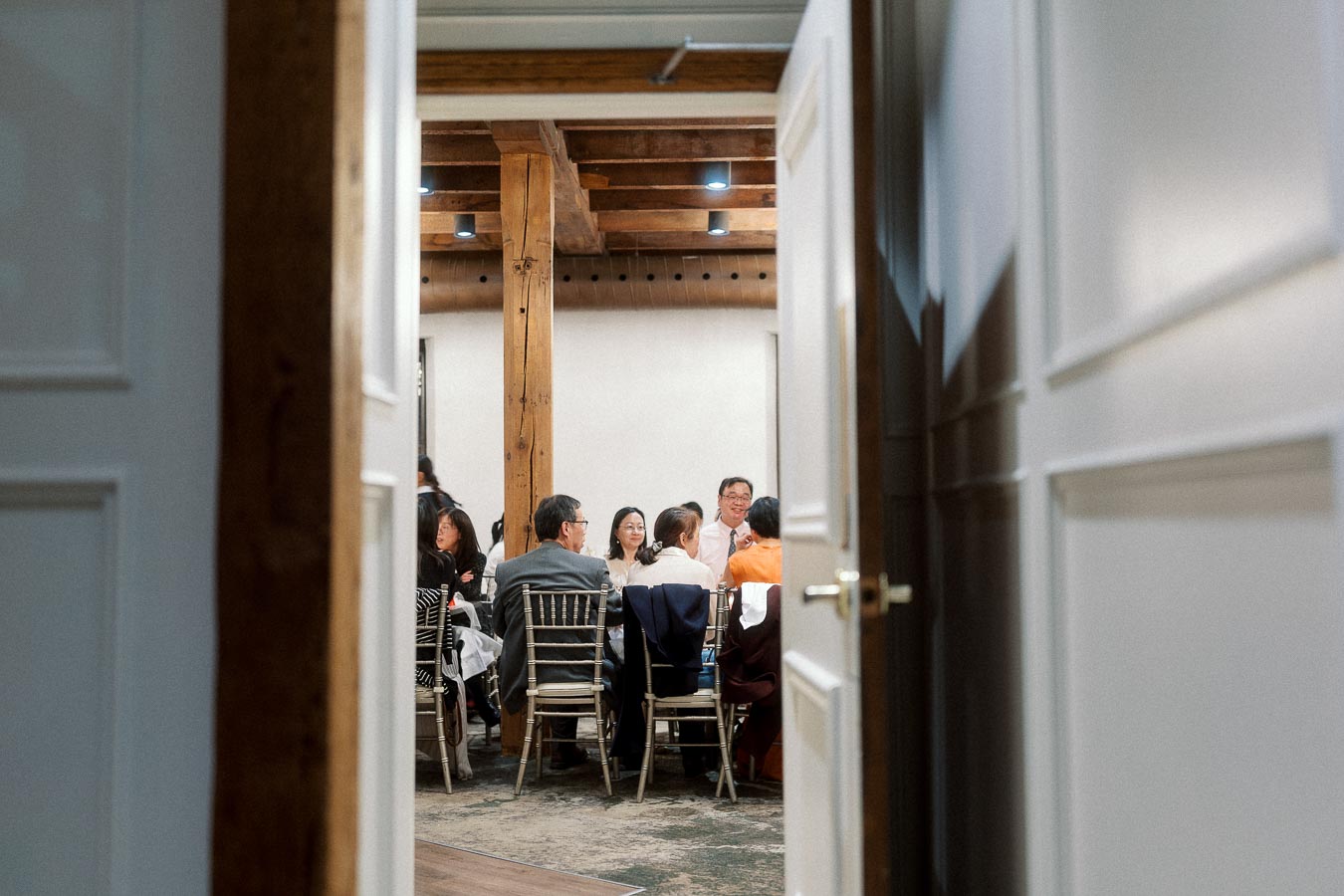Guests seated at round tables inside an event space, viewed through open doors.