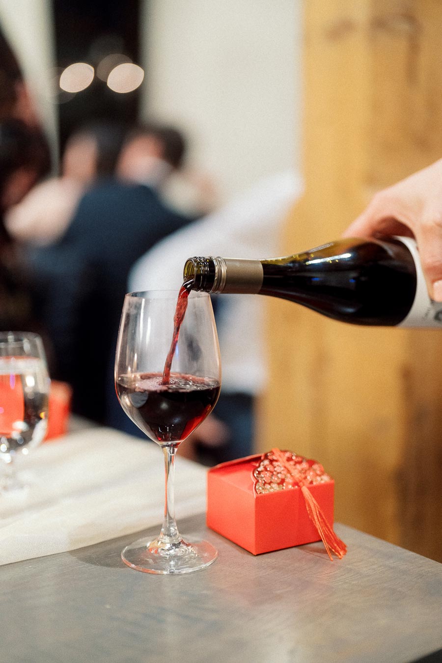 Red wine being poured into a glass beside a small red gift box