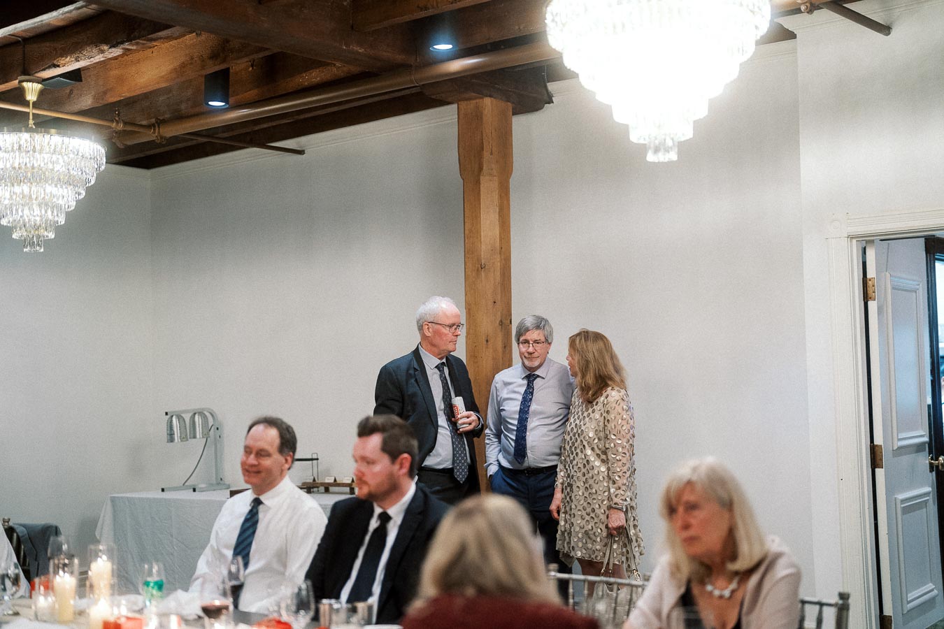 Guests mingling indoors beneath chandeliers during an engagement celebration
