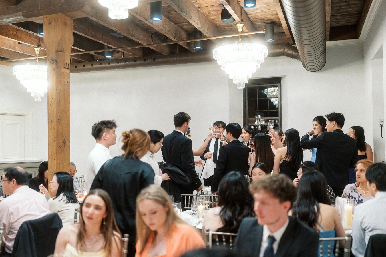 Guests raise glasses for a toast during a formal indoor celebration.