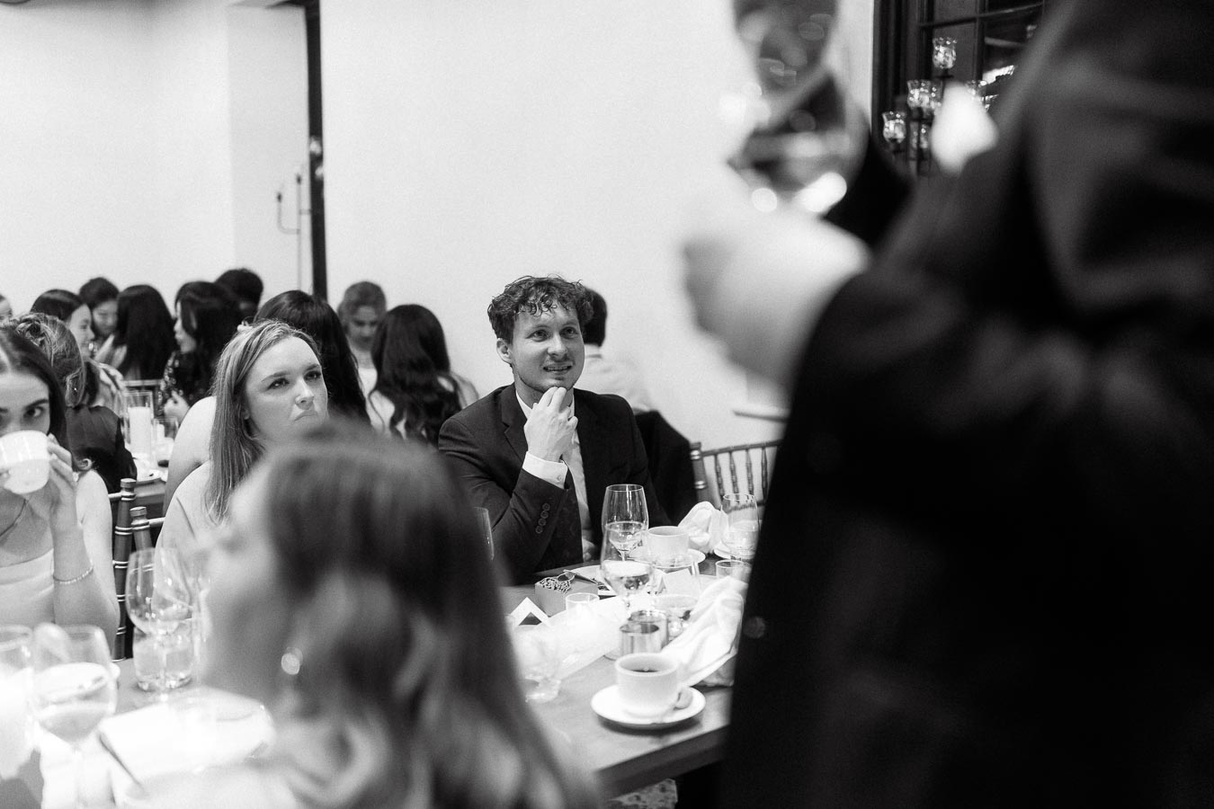 Guests seated at a formal dinner listening to a toast