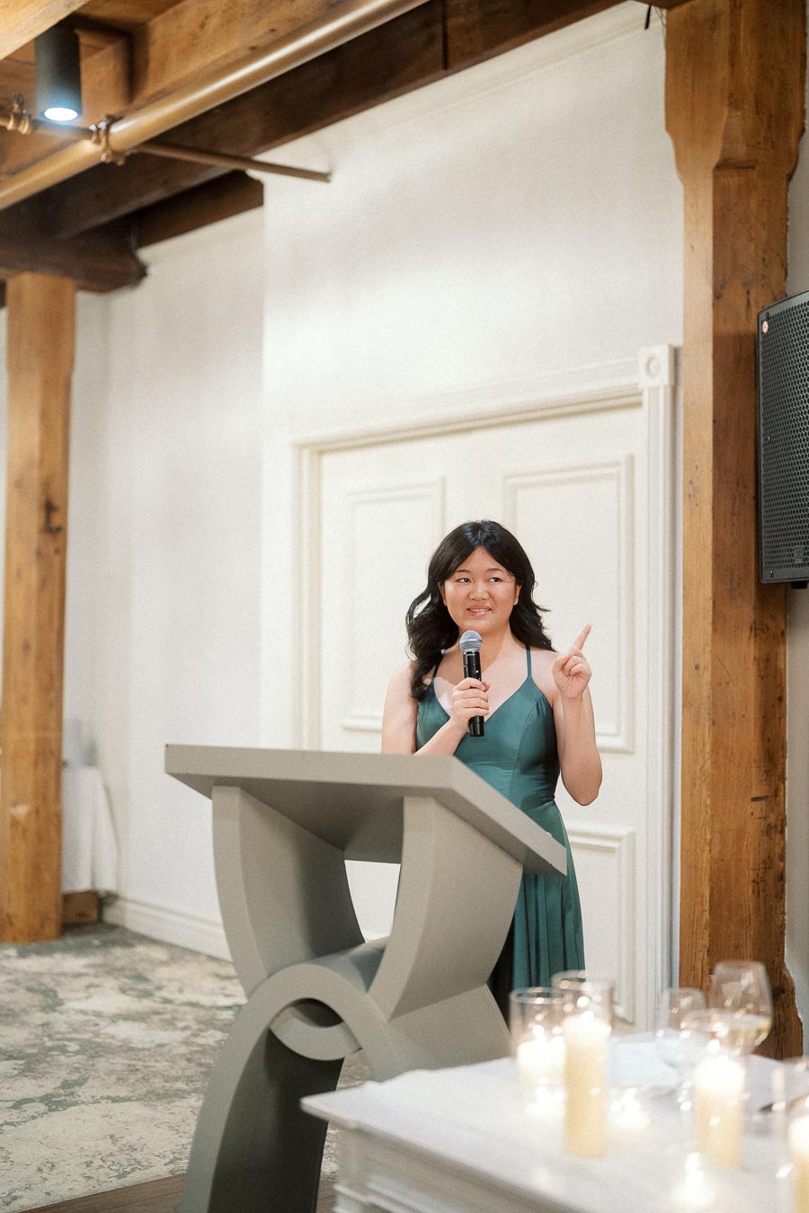 Woman in a green dress giving a speech at a podium with a microphone