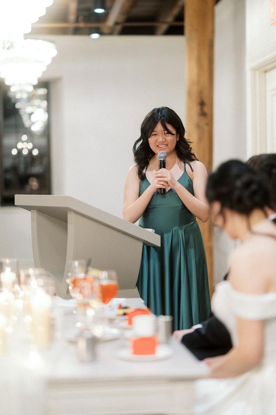 Woman in green dress gives a speech at a reception podium