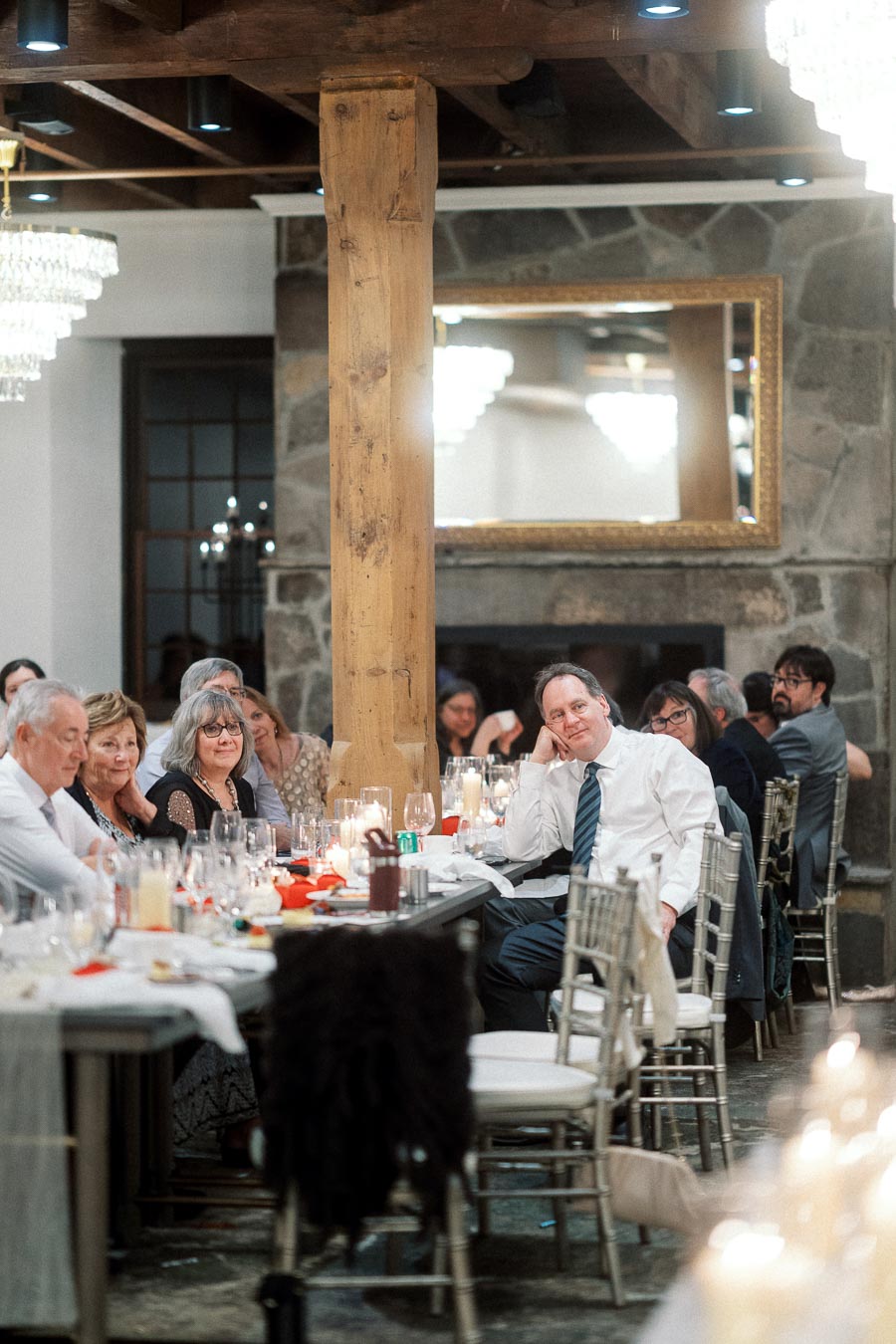 Guests seated at long reception tables in a rustic stone and wood dining room
