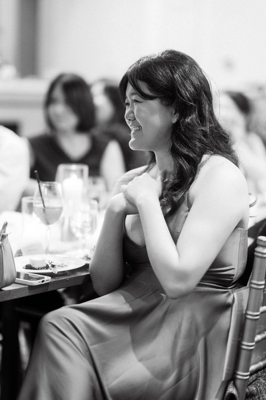Woman in a formal dress smiling while seated at a reception table