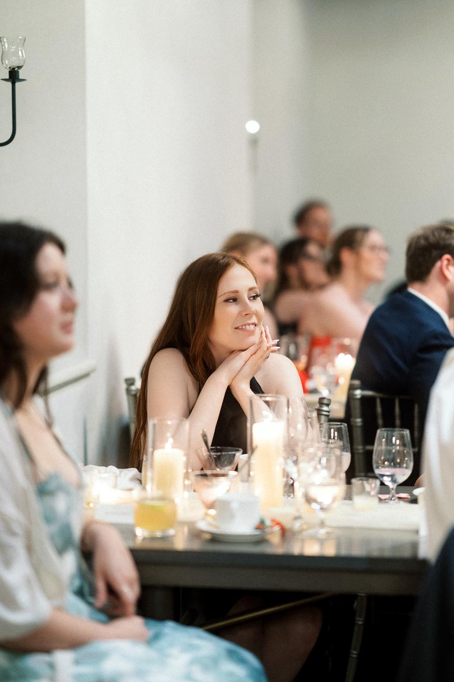 Guest smiling at a candlelit dinner table during an engagement celebration