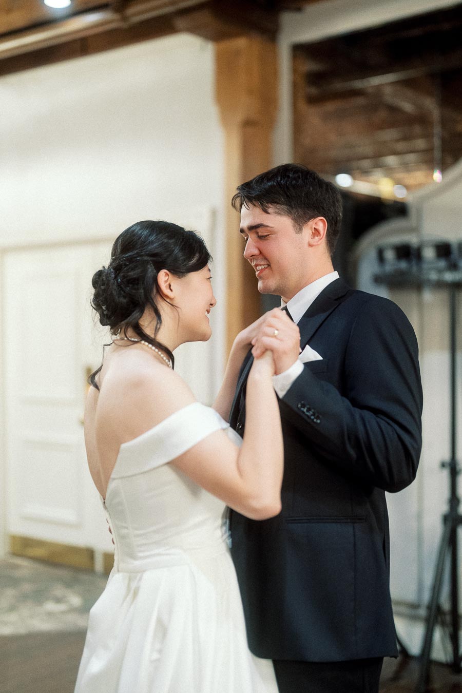 Couple in formal attire holding hands and smiling indoors during an engagement photoshoot