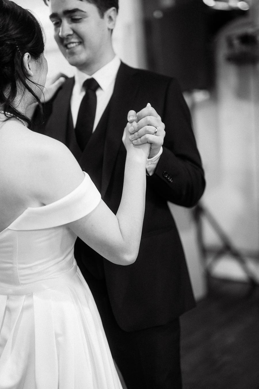 Couple in formal attire holding hands and dancing indoors