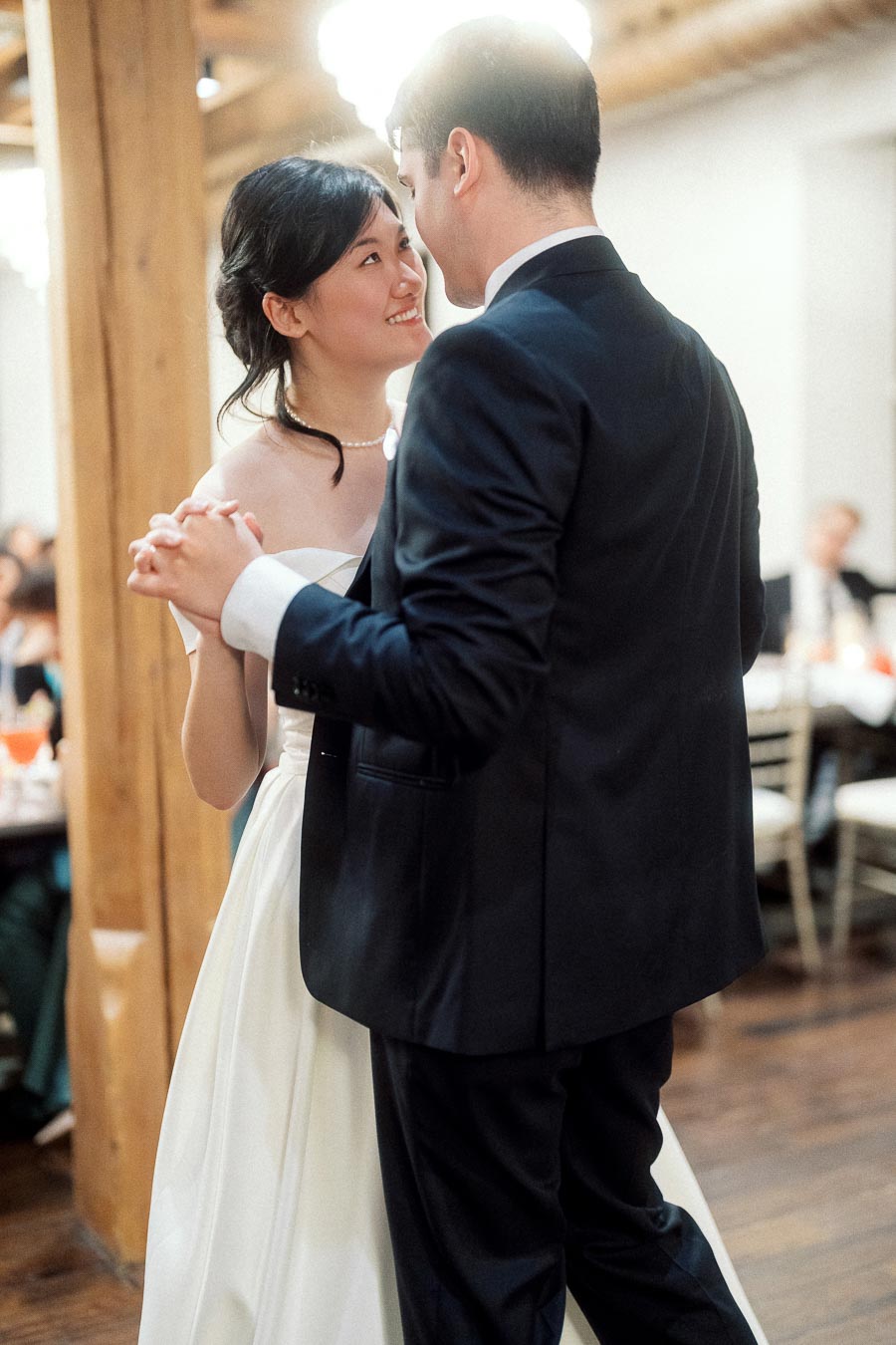 Couple in formal attire dancing together at an indoor reception.