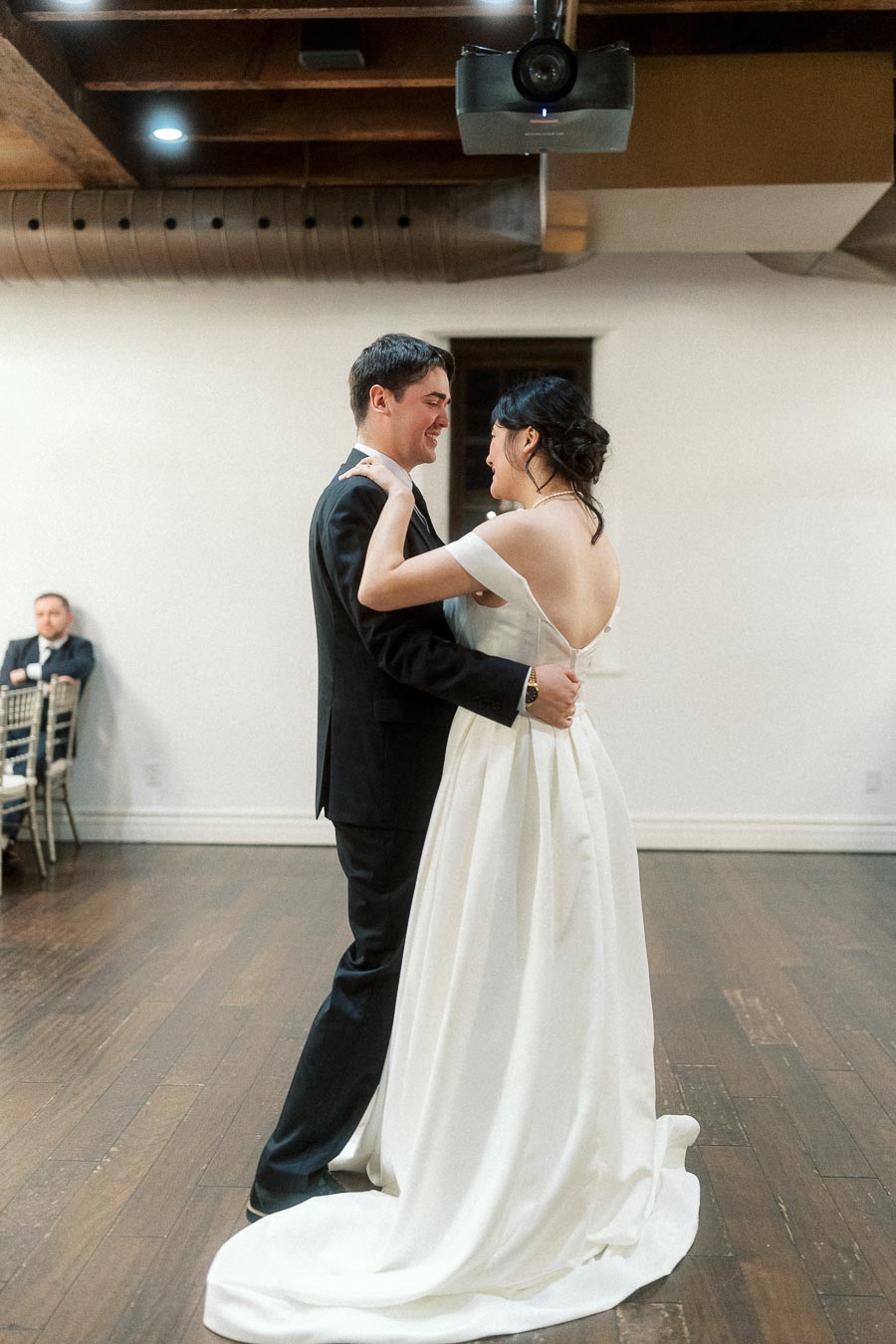 Couple in formal attire slow dancing on an indoor wooden dance floor