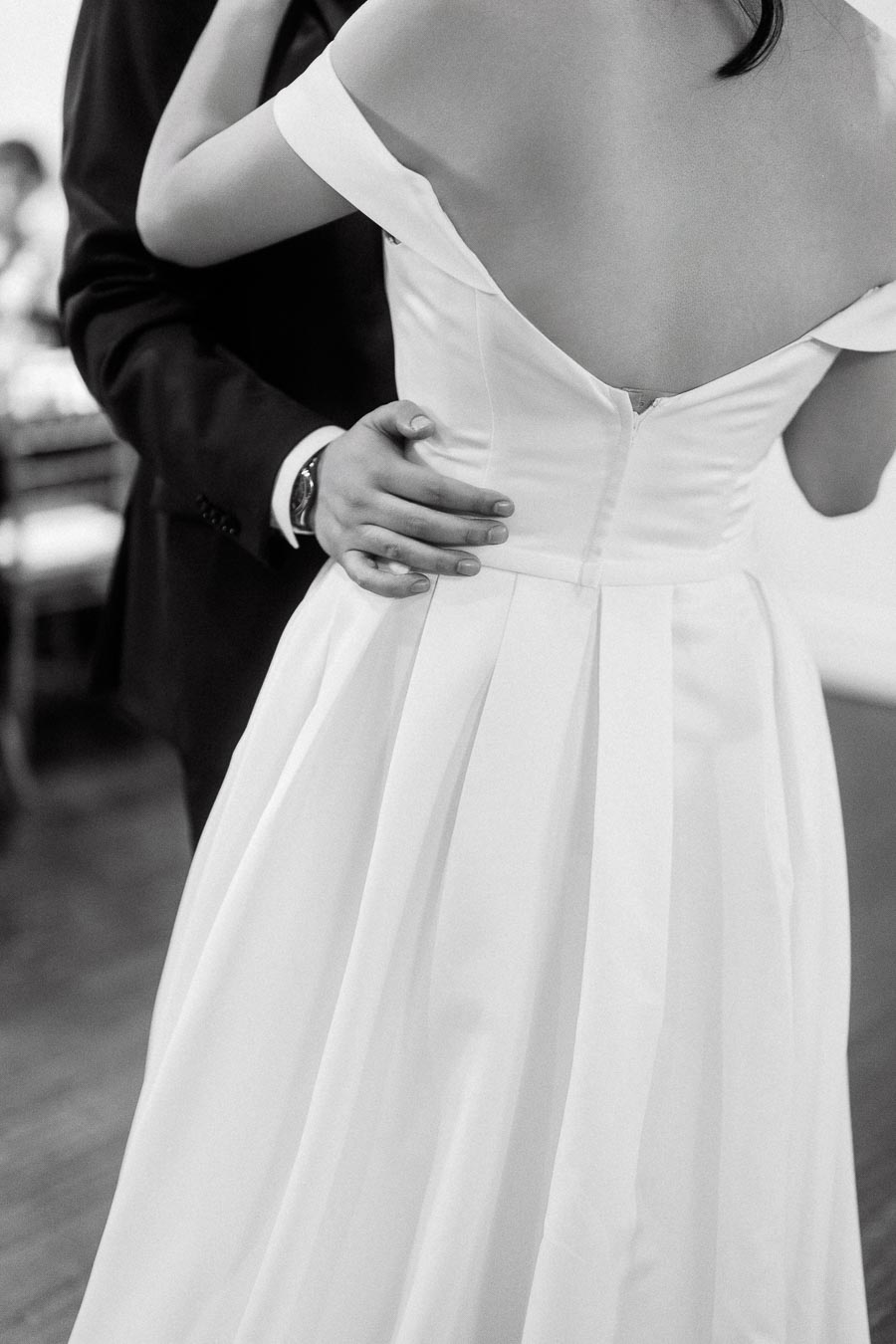Close-up of a couple embracing, focused on a white off-the-shoulder dress