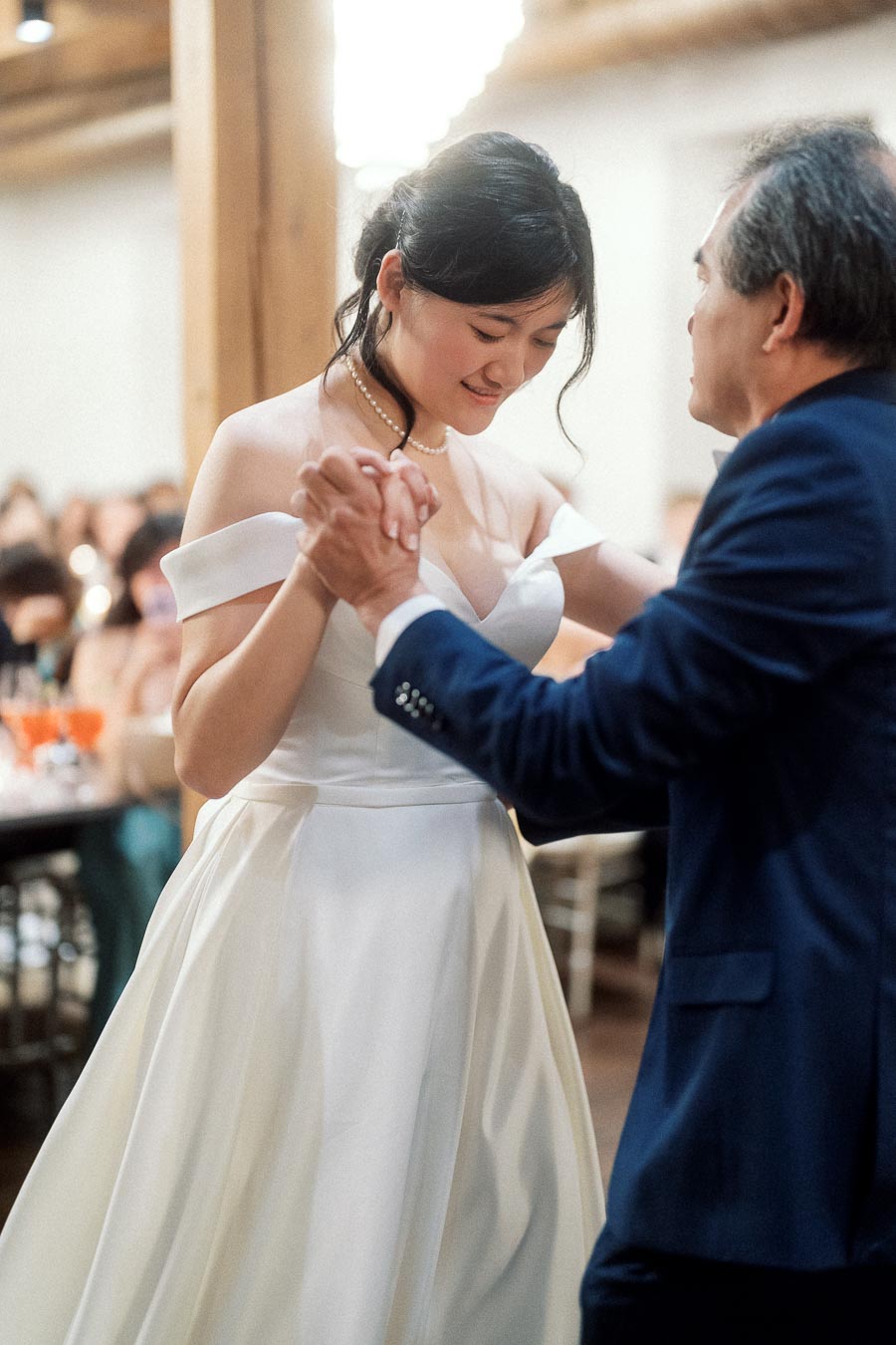 Woman in a white gown dancing with an older man at an indoor reception