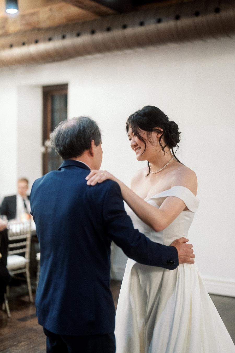 Couple in formal wedding attire dancing together indoors at a reception