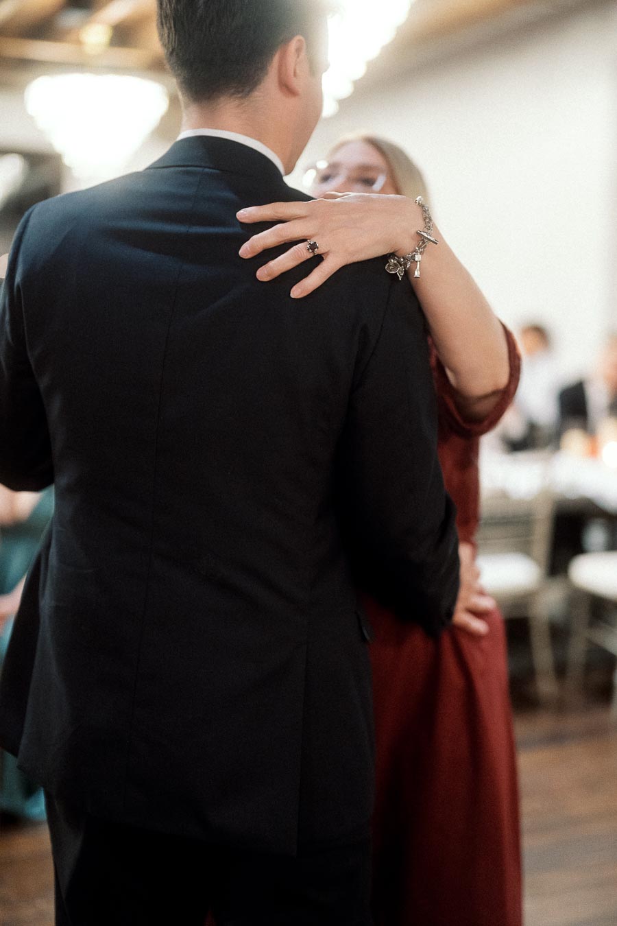 Couple slow dancing indoors, with an engagement ring visible on her hand