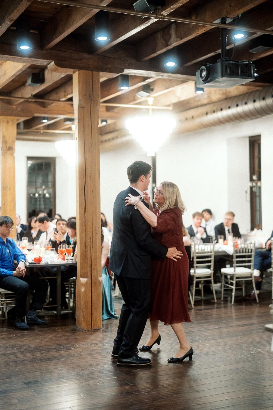 Couple dancing together on a wooden floor during an indoor reception