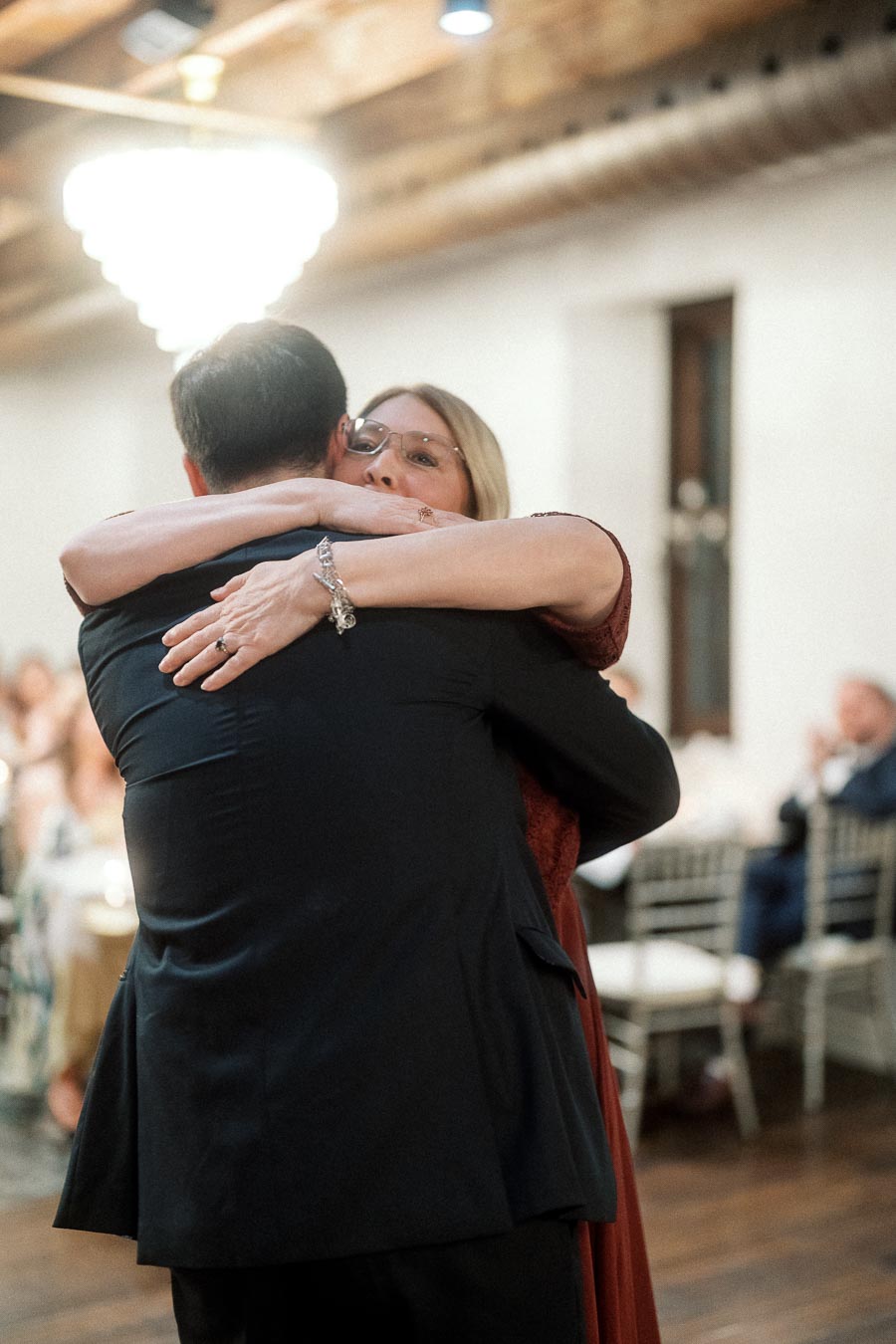 Two people embrace on a dance floor during an indoor celebration.