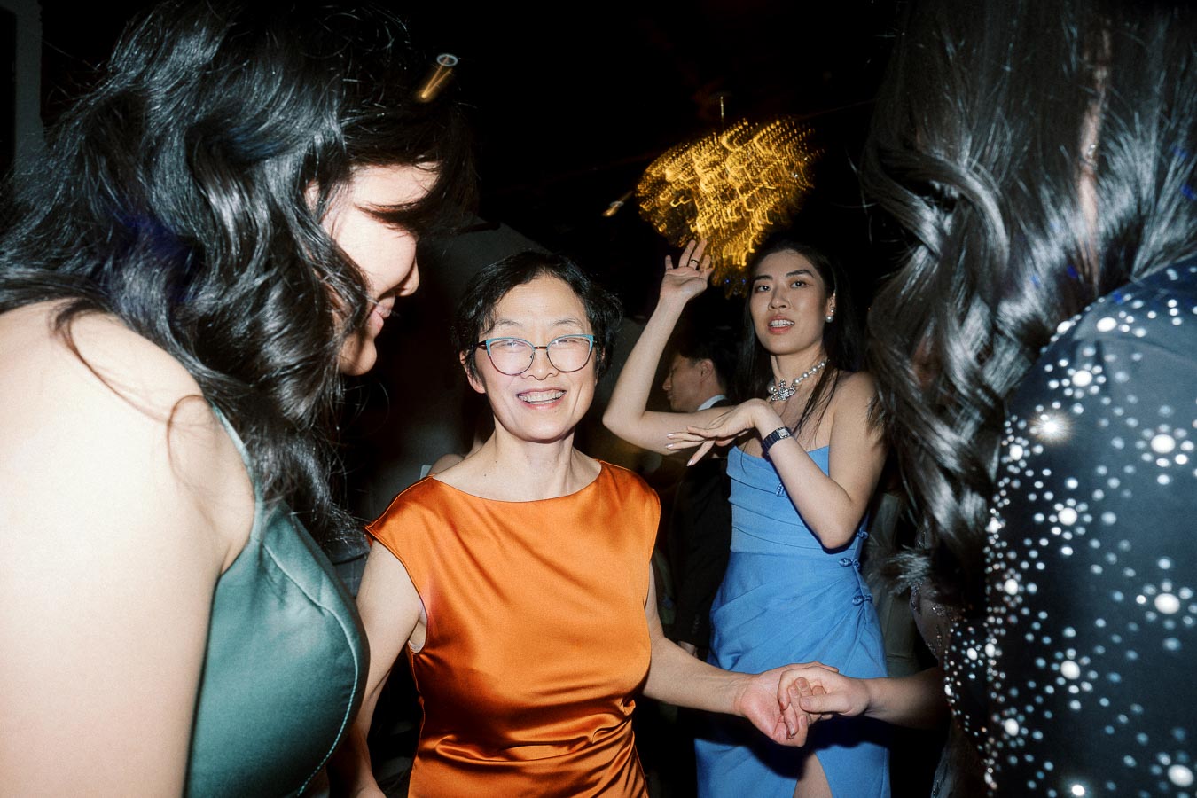 Guests in formal dresses dancing and holding hands at a lively evening celebration