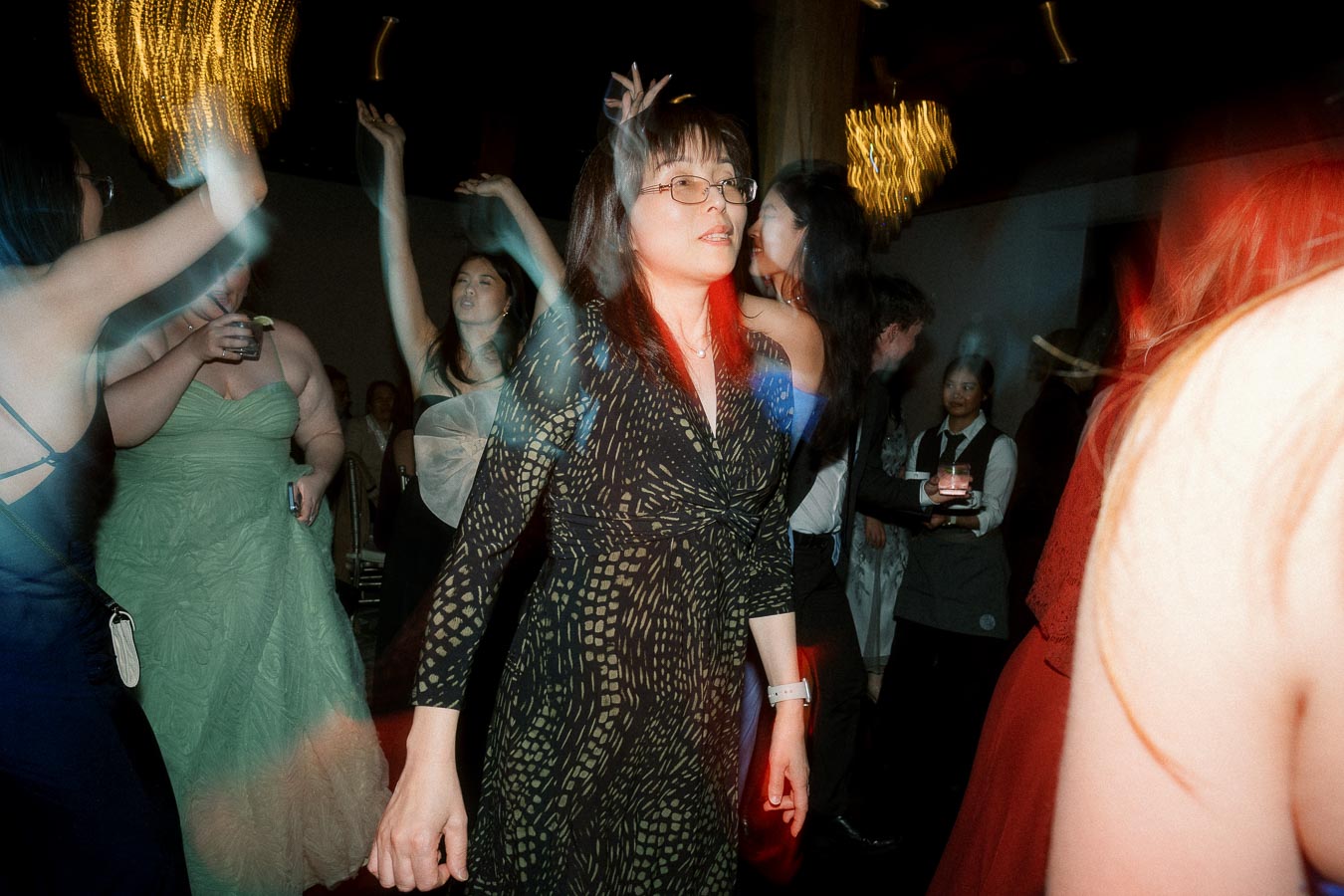 Guests dancing on a dimly lit reception dance floor with colorful motion blur.