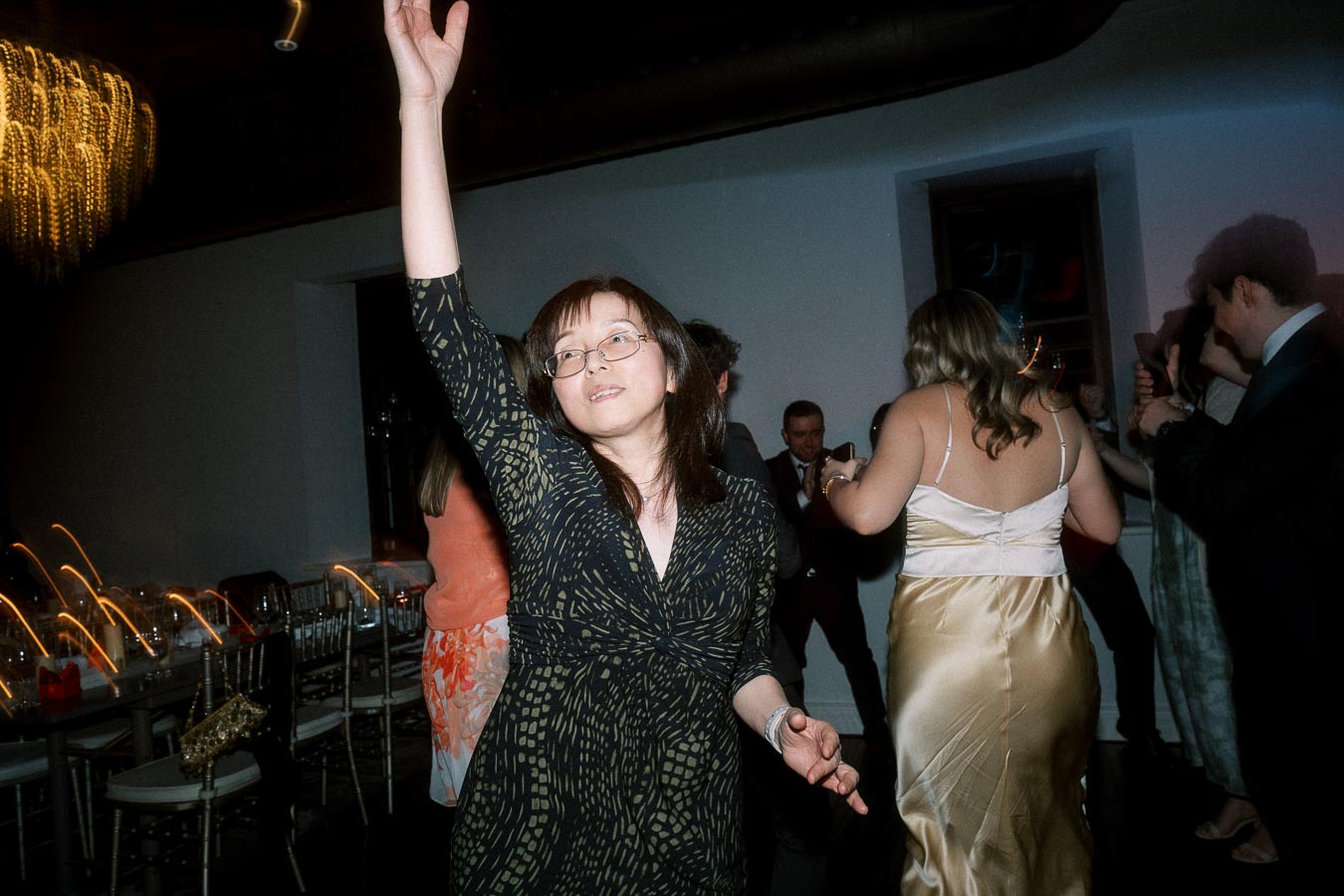 Guest dancing with one arm raised during an indoor evening celebration