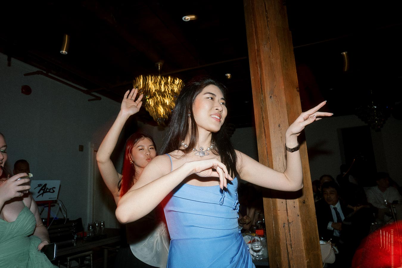 Woman in a blue dress dancing indoors at a lively evening celebration