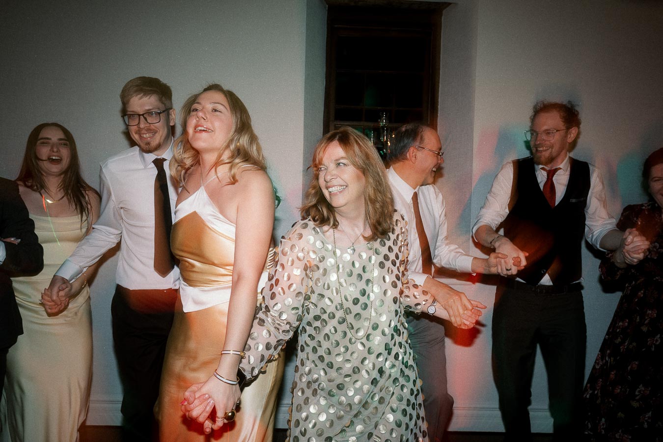 Guests holding hands and dancing together at an indoor celebration
