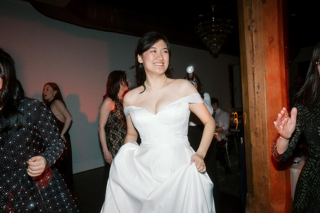 Bride in an off-the-shoulder white gown smiling while dancing indoors