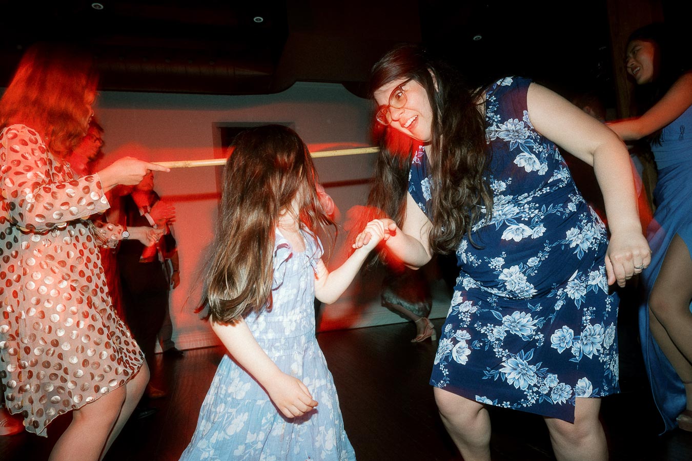 Woman and young girl holding hands while dancing at an indoor party